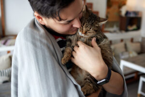 Young man in t shirt holding a cat.